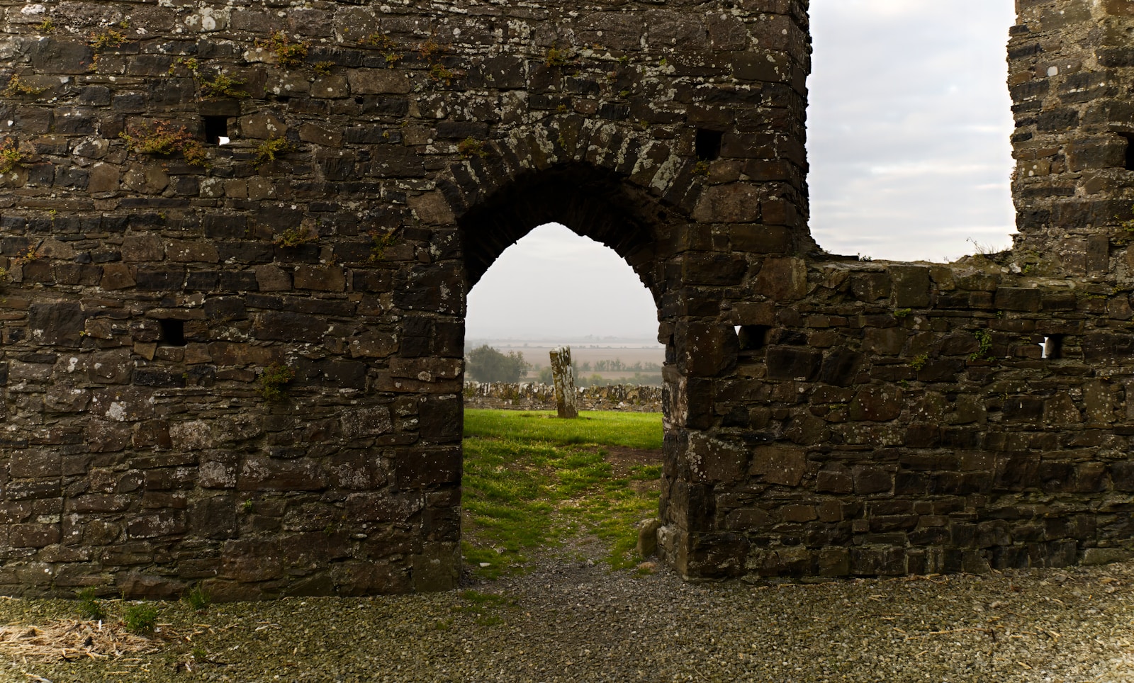 A stone wall with an arched doorway in the middle of it